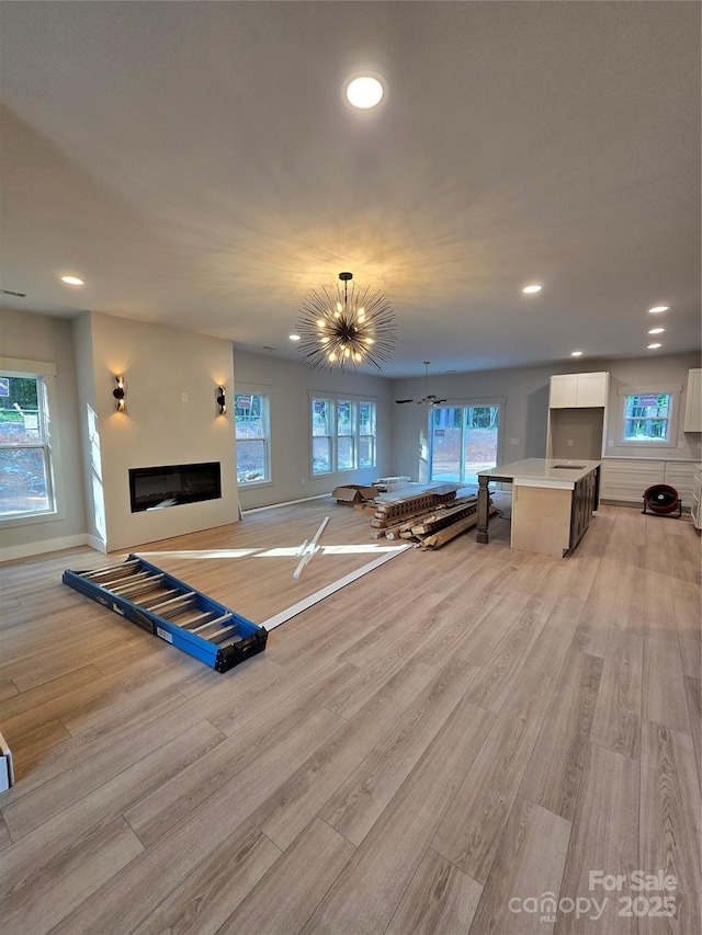 44389 US-52 Hwy N, Richfield, NC 28137 - living area featuring light wood-style floors, a glass covered fireplace, recessed lighting, baseboards, and a chandelier