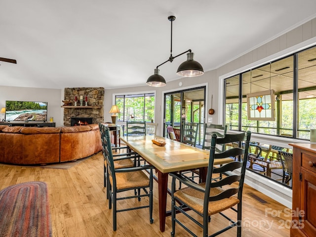 1973 Buffalo Creek Rd, Lake Lure, NC 28746 - dining room with light wood-type flooring, visible vents, and a stone fireplace
