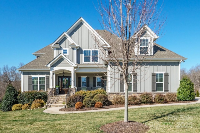 craftsman inspired home featuring board and batten siding, roof with shingles, and a front lawn