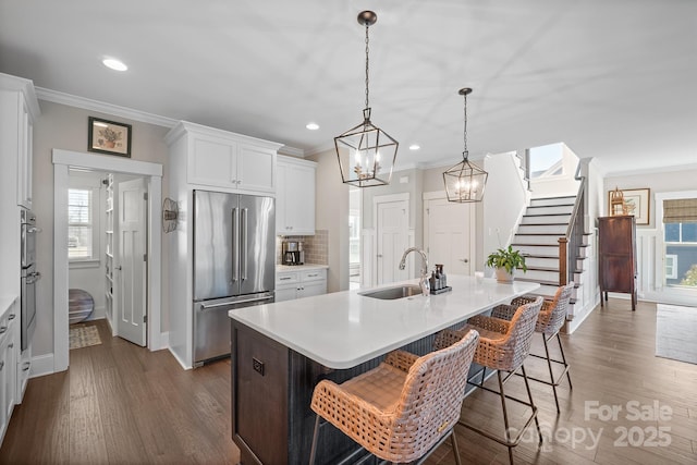 kitchen with a wealth of natural light, appliances with stainless steel finishes, a sink, and ornamental molding