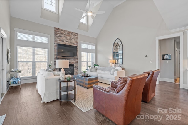 living area with a healthy amount of sunlight, ceiling fan, a fireplace, and dark wood-type flooring