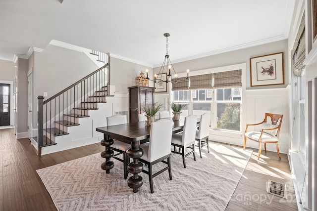 dining room featuring stairway, wood finished floors, a wealth of natural light, and a notable chandelier