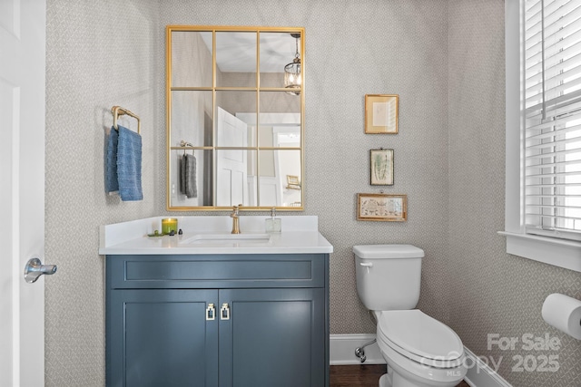 bathroom featuring baseboards, vanity, and toilet