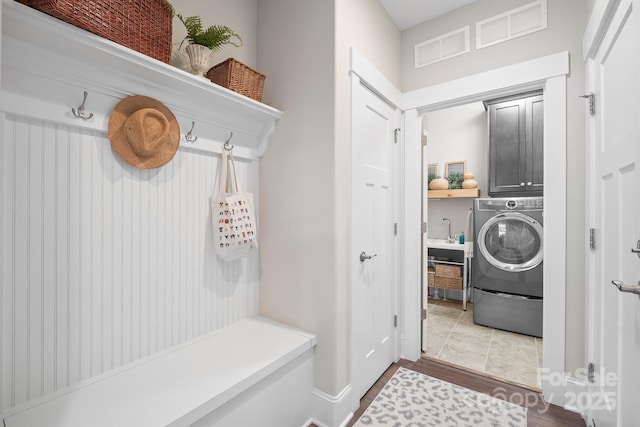 mudroom with visible vents, wood finished floors, a sink, and washer / dryer