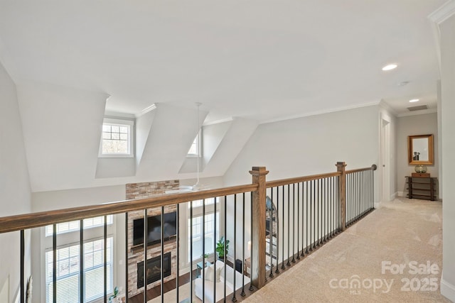 hallway with baseboards, visible vents, lofted ceiling, crown molding, and carpet floors