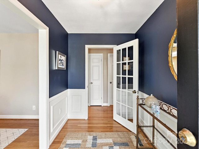 entrance foyer featuring wood finished floors, a wainscoted wall, and french doors