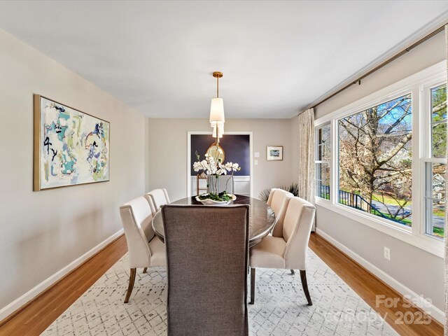 dining room with light wood-style flooring, a notable chandelier, and baseboards