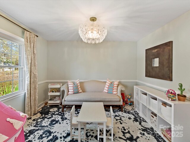 living area with baseboards and a chandelier