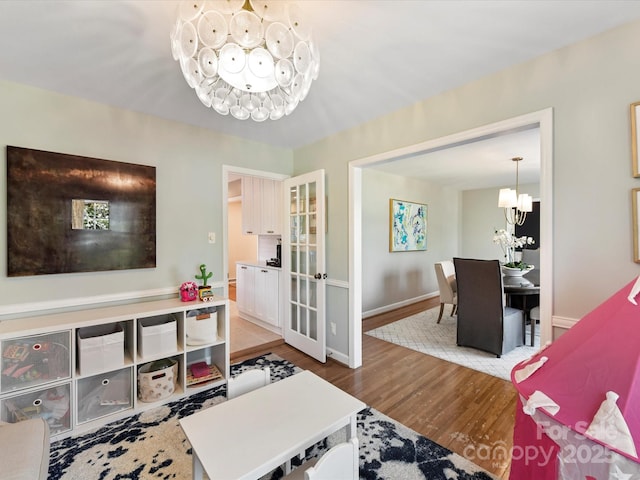 living room with baseboards, an inviting chandelier, and wood finished floors