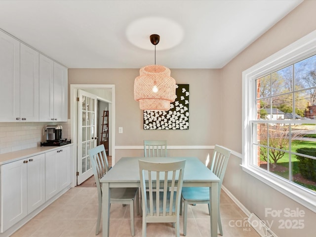 dining space with a wealth of natural light, baseboards, and light tile patterned floors