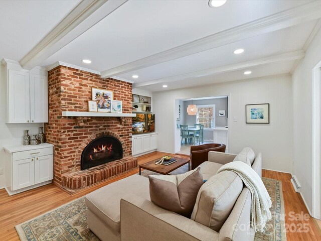 living room featuring a brick fireplace, beamed ceiling, and light wood-style flooring