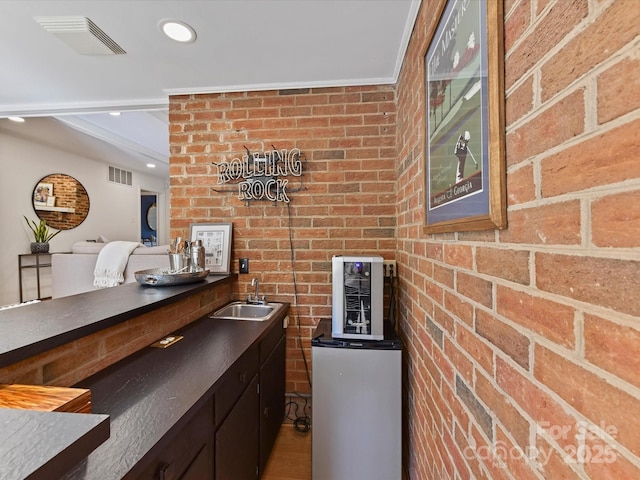 bar featuring visible vents, brick wall, and a sink