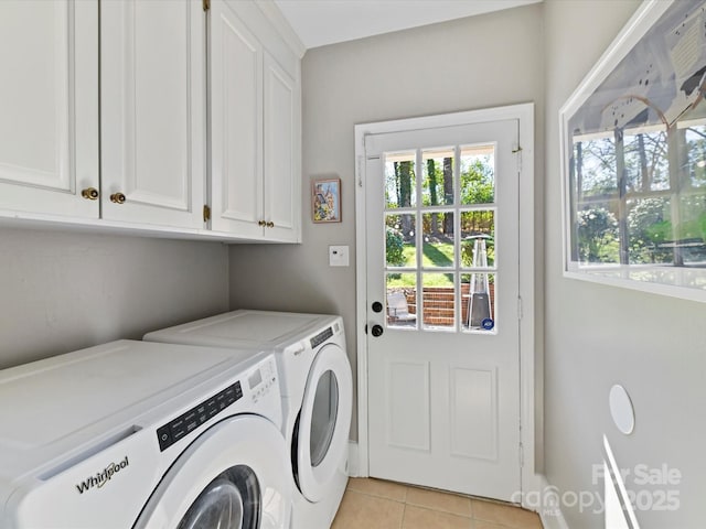 clothes washing area featuring washer and dryer, light tile patterned floors, and cabinet space