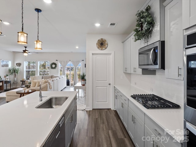 kitchen with visible vents, dark wood-type flooring, stainless steel appliances, light countertops, and a sink