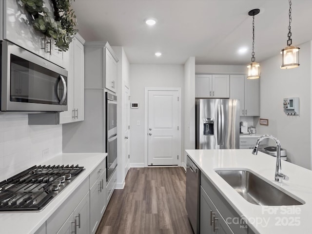 kitchen with stainless steel appliances, light countertops, a sink, and dark wood-style floors