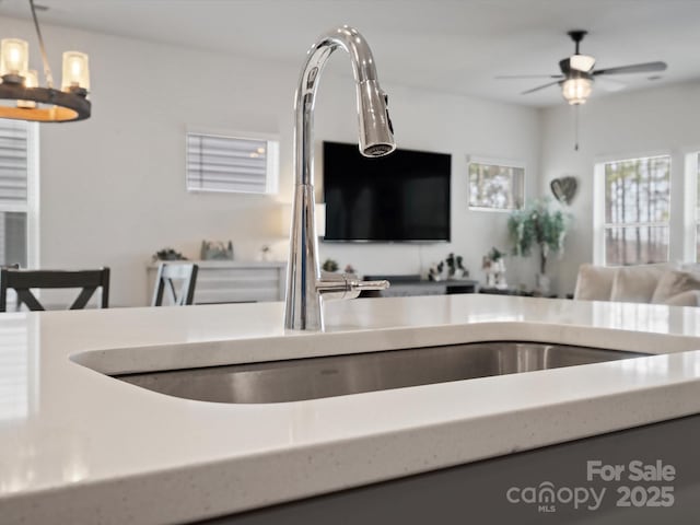 kitchen with open floor plan, ceiling fan with notable chandelier, and pendant lighting