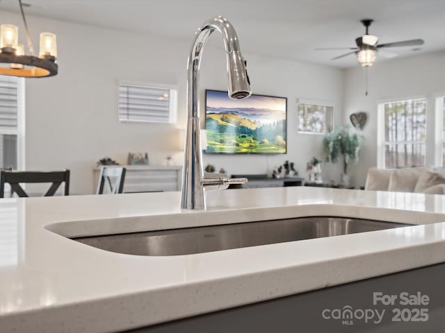 kitchen with open floor plan, ceiling fan with notable chandelier, and pendant lighting