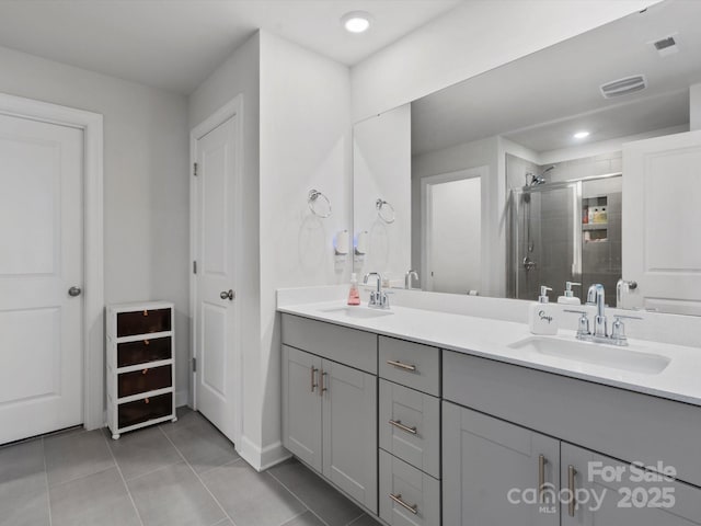 bathroom featuring double vanity, a stall shower, tile patterned flooring, and a sink