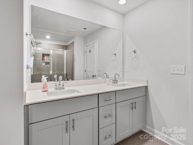 bathroom with a sink, a shower stall, baseboards, and double vanity