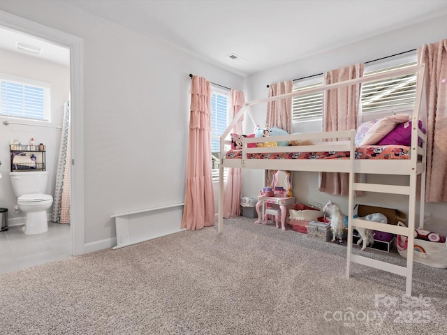 carpeted bedroom featuring baseboards, visible vents, and ensuite bath