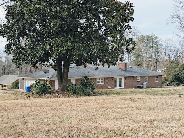 view of front of property with brick siding, a chimney, and a front yard