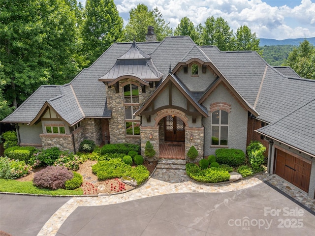 view of front of house with a garage, a chimney, metal roof, a standing seam roof, and stucco siding