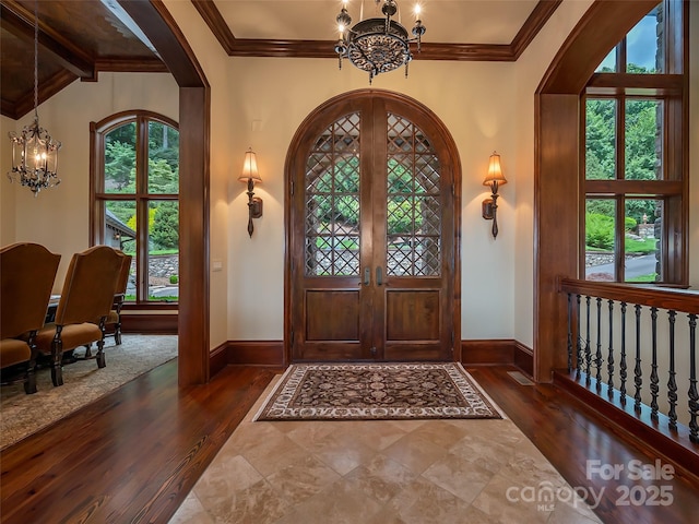 entrance foyer with an inviting chandelier, arched walkways, and french doors