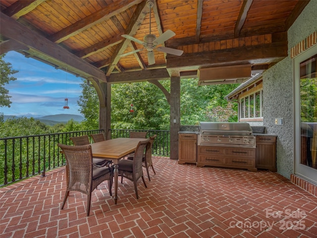 view of patio featuring ceiling fan, outdoor dining area, a mountain view, area for grilling, and a gazebo