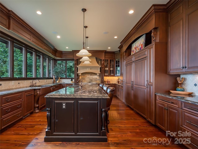 kitchen with glass insert cabinets, dark wood-style flooring, a kitchen island with sink, and custom exhaust hood