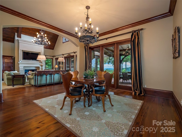 dining space featuring an inviting chandelier, a lit fireplace, baseboards, and hardwood / wood-style flooring