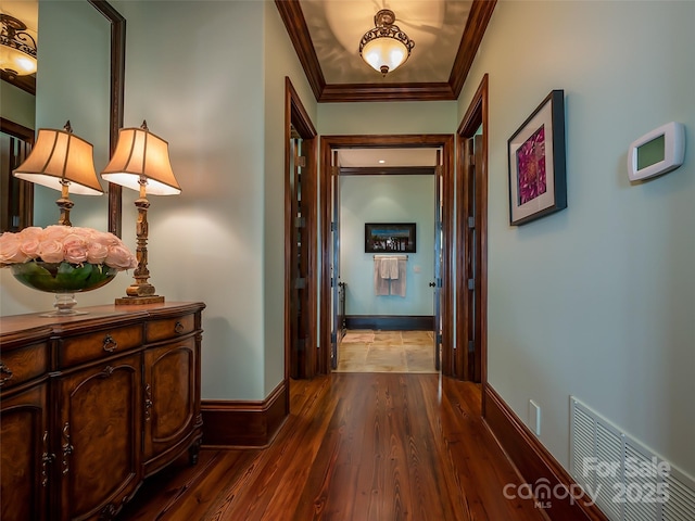 hall with baseboards, wood finished floors, visible vents, and crown molding