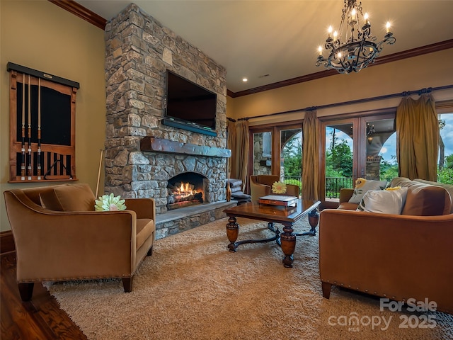 living room with a stone fireplace, ornamental molding, wood finished floors, and a notable chandelier