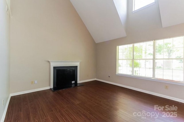 unfurnished living room featuring a fireplace with raised hearth, high vaulted ceiling, dark wood-type flooring, and baseboards