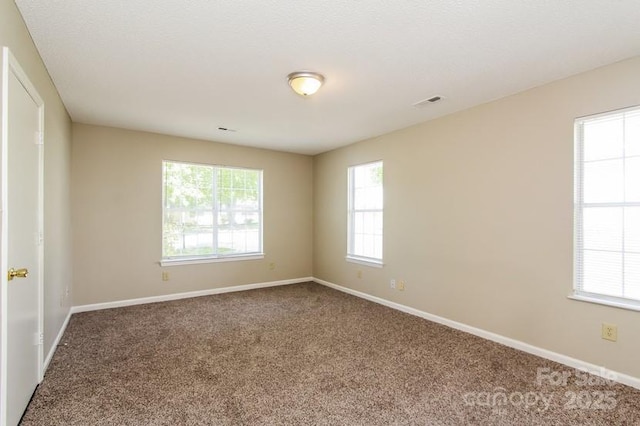 empty room with carpet flooring, visible vents, and baseboards