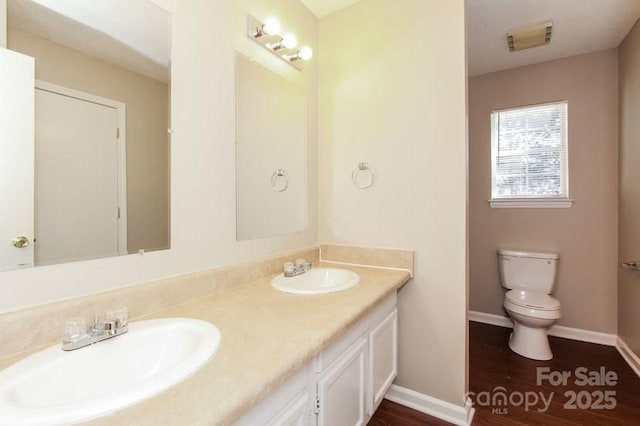 full bath featuring toilet, double vanity, visible vents, and a sink