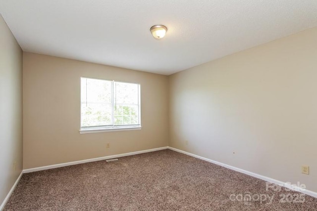 carpeted spare room with visible vents and baseboards