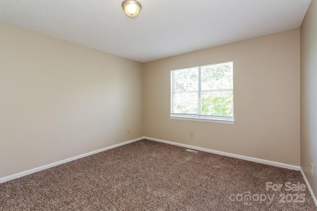 carpeted empty room featuring baseboards