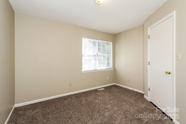 unfurnished room with visible vents, baseboards, and dark colored carpet