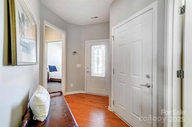 foyer entrance featuring light wood-style flooring, visible vents, and baseboards