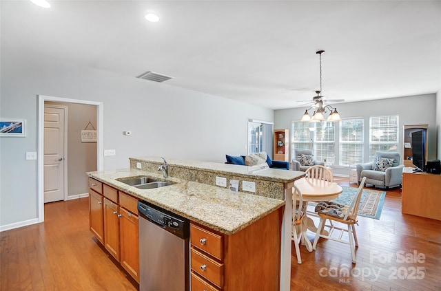 kitchen featuring dishwasher, open floor plan, light wood-type flooring, and a sink