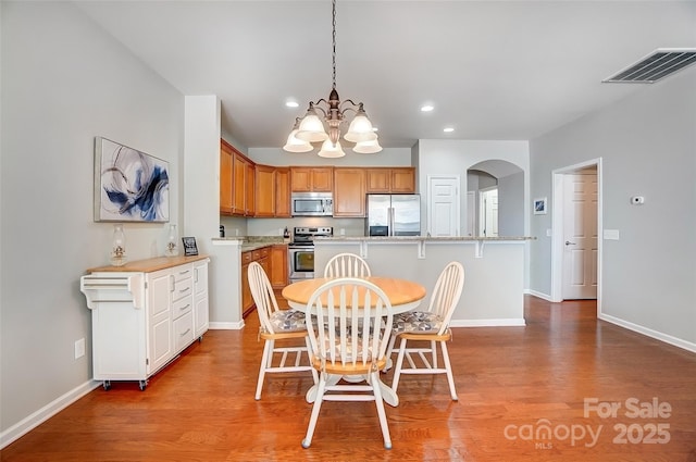 dining space featuring arched walkways, visible vents, baseboards, and wood finished floors