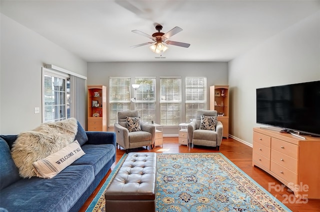 living area with wood finished floors, a ceiling fan, and baseboards