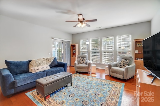 living room with visible vents, ceiling fan, and wood finished floors