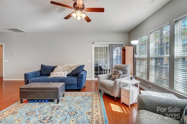 living room featuring baseboards, visible vents, ceiling fan, and wood finished floors