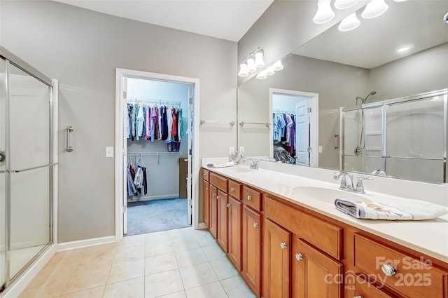 full bath featuring a sink, double vanity, a shower stall, and tile patterned floors