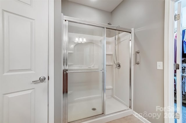 bathroom featuring a shower stall and a walk in closet