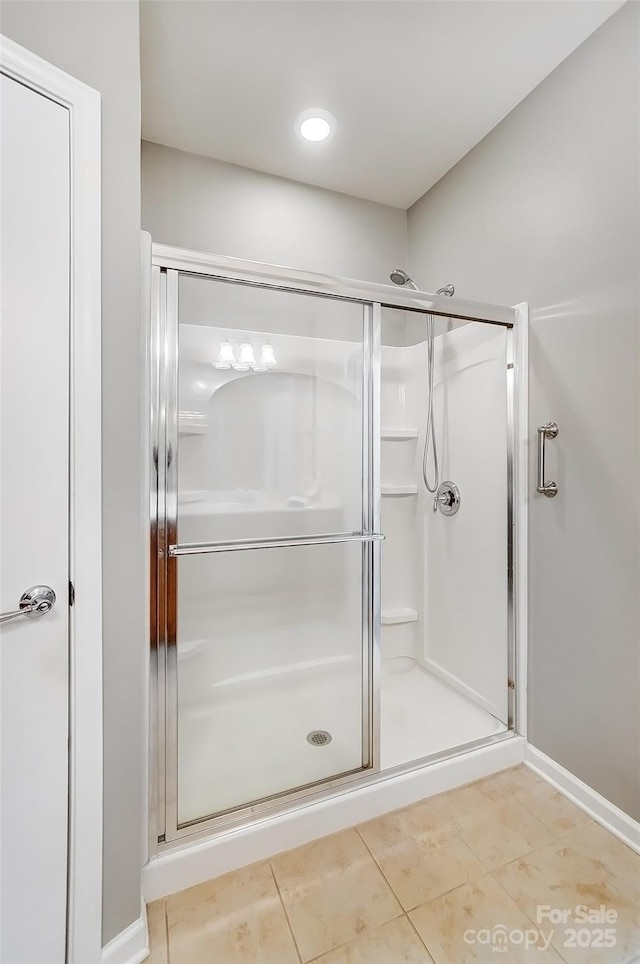 full bath with a stall shower, tile patterned flooring, and baseboards