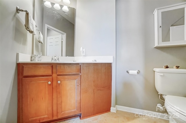 bathroom featuring toilet, vanity, baseboards, and tile patterned floors