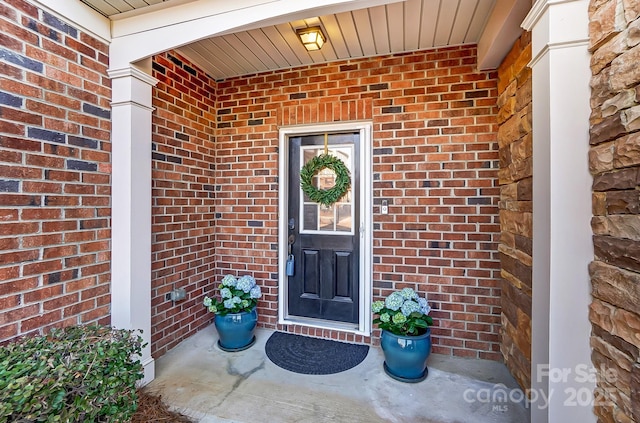 doorway to property with brick siding and a porch