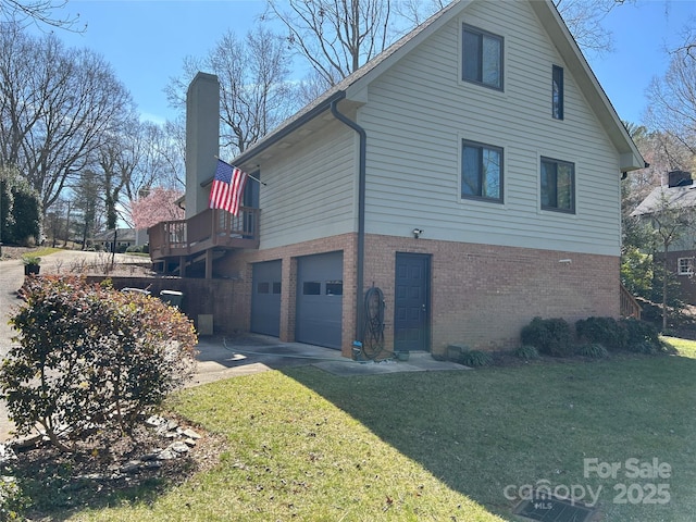 view of side of property featuring driveway, a yard, a garage, brick siding, and a chimney